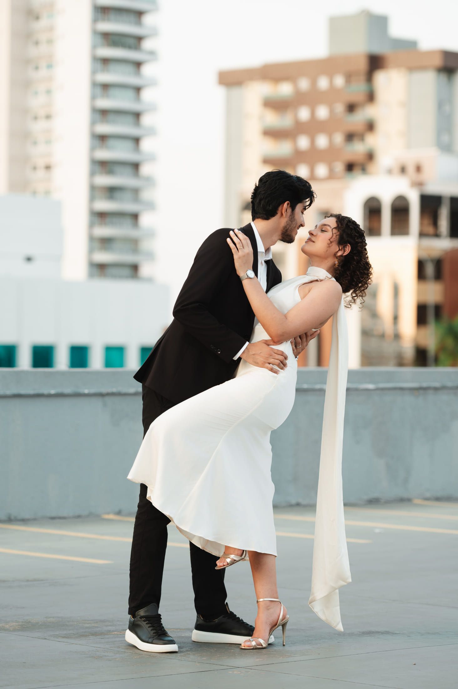 Maria e Italo se beijando num terraço, com os prédios da cidade atrás